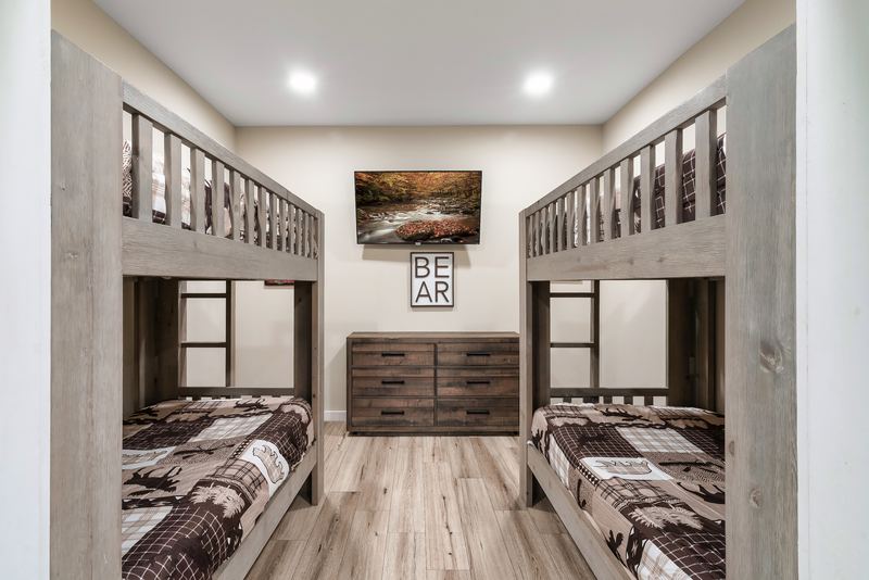 Lower-level bunk room with two twin-over-twin bunk beds, a dresser and a TV