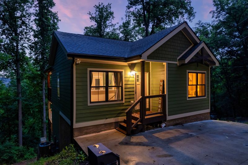 Front porch steps with a wooden welcome sign, the cabin lit at dusk