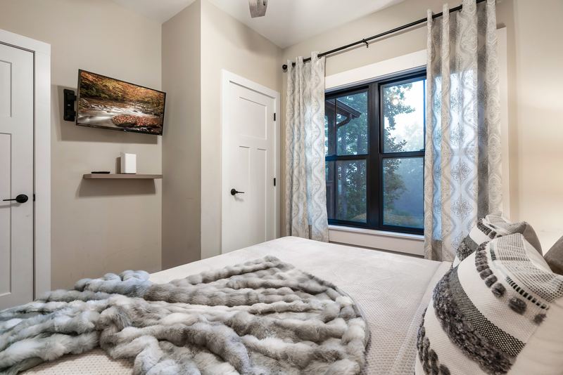 King bedroom with a wall-mounted TV and a window