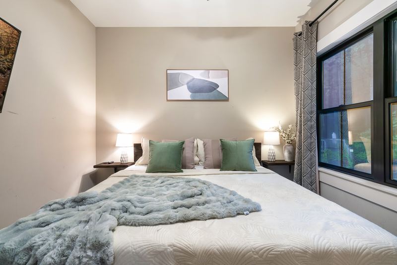 Second main-level king bedroom with green pillows and a large window