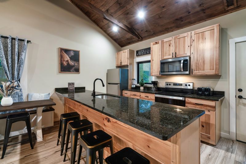 Kitchen with a granite island, four stools, wood cabinets and stainless appliances