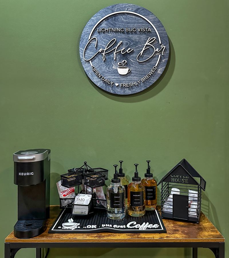 Round Lightning Bug Vista coffee bar sign over a Keurig and coffee station on a green wall