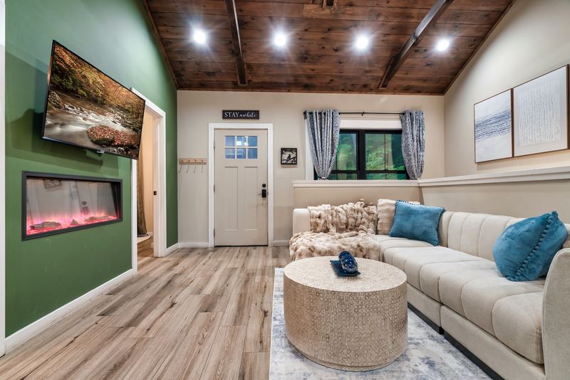 Electric fireplace with a TV above it on a green accent wall, beside the sectional