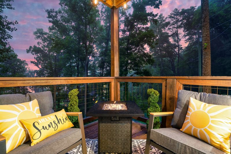Outdoor sofa and chairs around a propane fire table on the lower deck at dusk