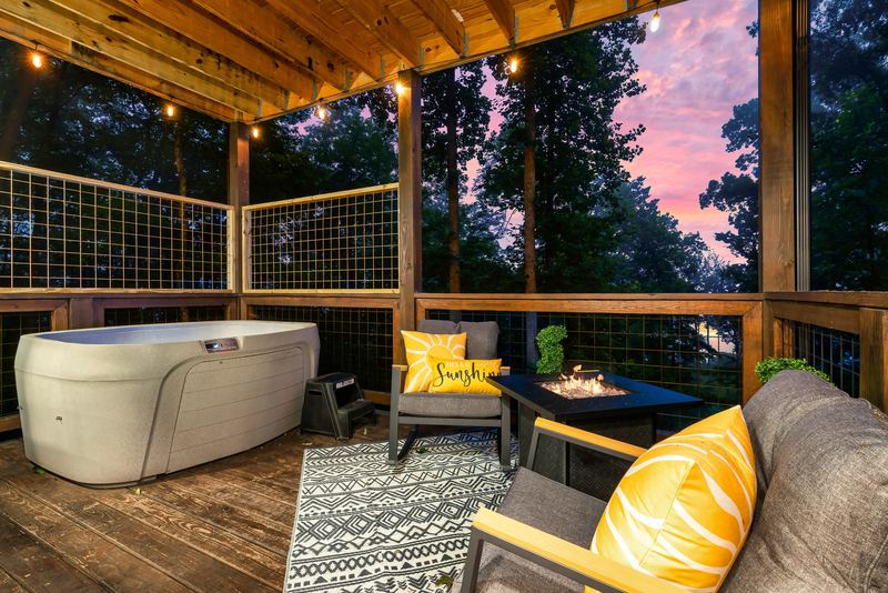 Covered lower deck with the hot tub, a propane fire table and outdoor seating with yellow pillows