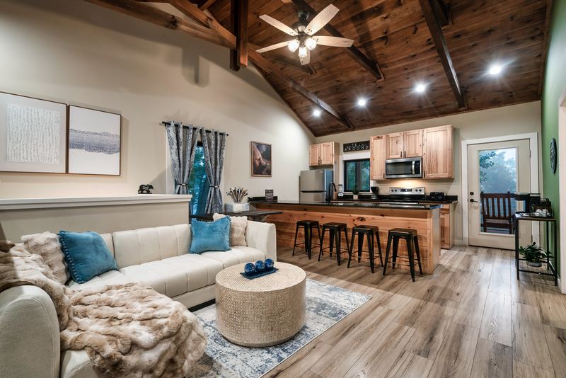 Open living room looking toward the kitchen island with four stools and the door to the deck
